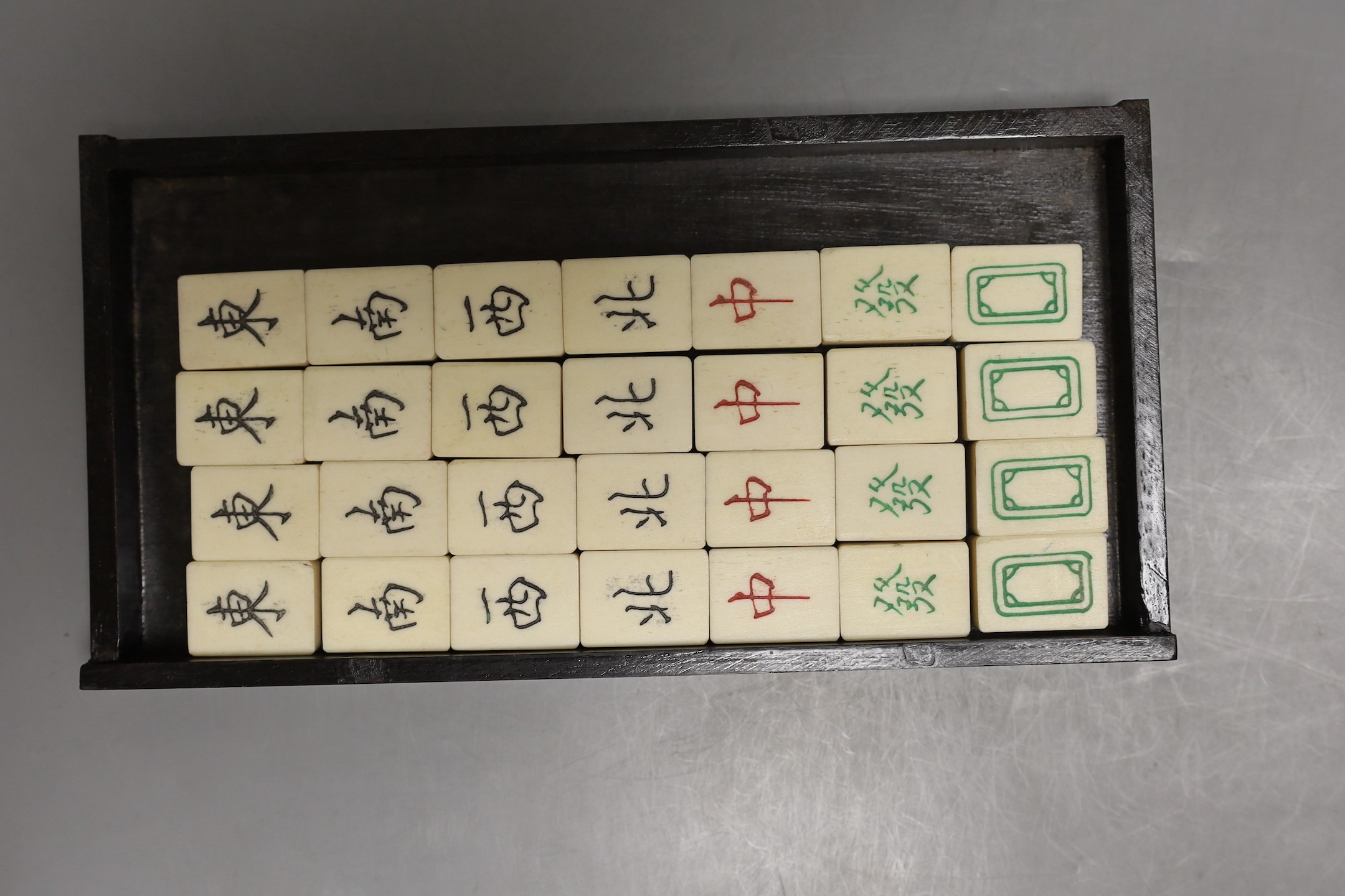 A Chinese boxed mahjong set, bone and bamboo gaming pieces, 24.5 cms wide x 16cms high.